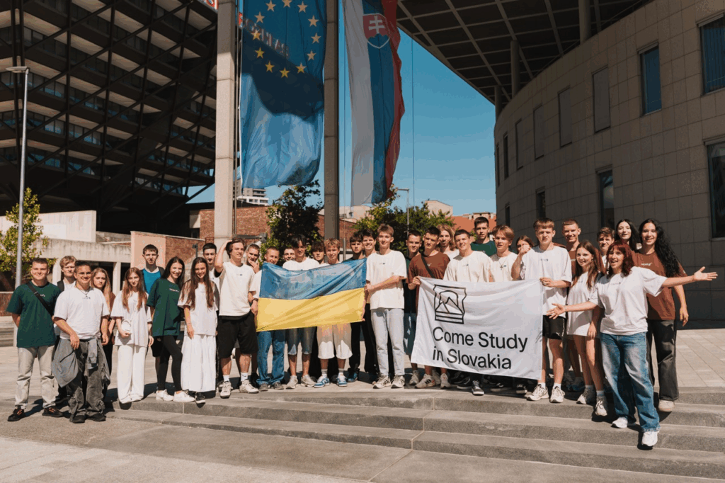 Українські студенти Come Study in Slovakia на груповому фото перед прапорами ЄС та Словаччини під час навчальної поїздки до Братислави